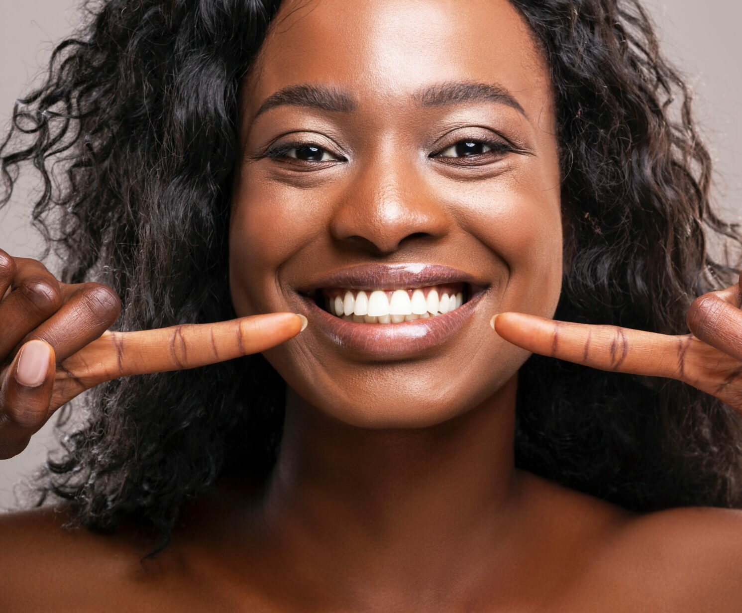 Happy woman pointing at her perfect white teeth